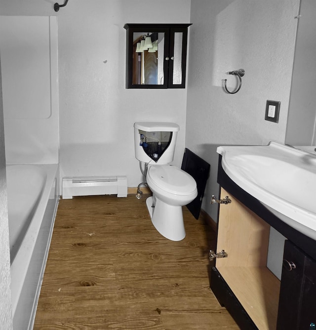 3756 Main St, Barnum, MN 55707 - bathroom featuring a baseboard heating unit, toilet, vanity, wood finished floors, and baseboards
