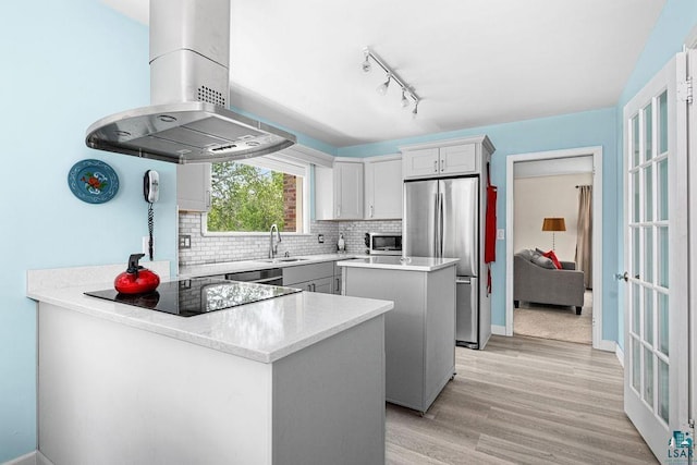 3319 E Superior St, Duluth, MN 55804 - kitchen featuring wall chimney exhaust hood, stainless steel appliances, a center island, a sink, and backsplash