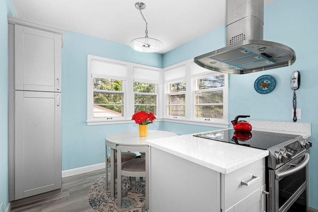 3319 E Superior St, Duluth, MN 55804 - kitchen with island range hood, double oven range, wood finished floors, white cabinetry, and baseboards
