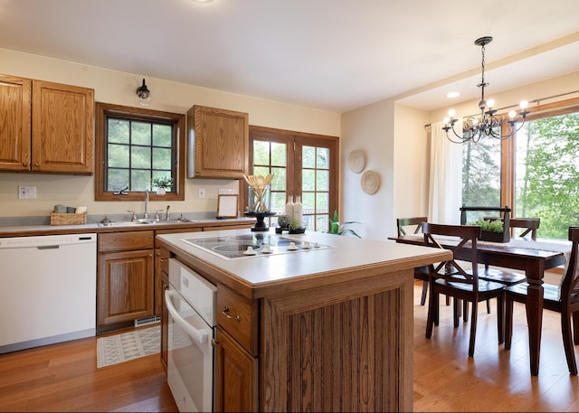 6220 N Tischer Rd, Duluth, MN 55804 - kitchen with white appliances, a sink, light wood-style flooring, a chandelier, and brown cabinetry