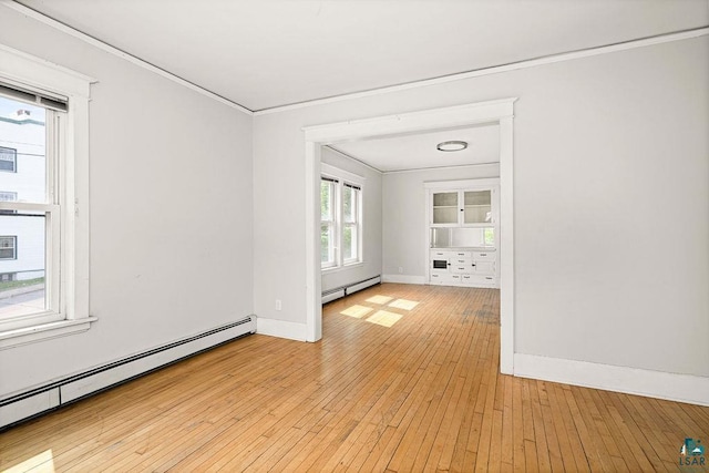 1901 E 5th St, Duluth, MN 55812 - empty room featuring a baseboard heating unit, ornamental molding, baseboards, and light wood-style flooring