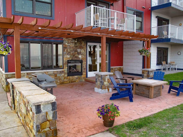 21 E Wisconsin St Unit 302, Grand Marais, MN 55604 - view of patio / terrace with an outdoor stone fireplace, a fire pit, a balcony, and a pergola