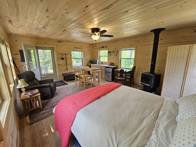 839 Loon Rd, Two Harbors, MN 55616 - bedroom featuring wooden walls, a wood stove, wood finished floors, wooden ceiling, and a sink