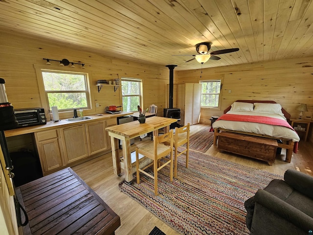 839 Loon Rd, Two Harbors, MN 55616 - bedroom featuring a wood stove, wooden walls, light wood-style flooring, a sink, and wood ceiling