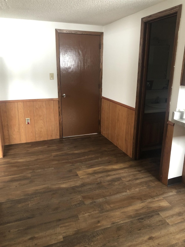 6509 Broadway St, Finlayson, MN 55735 - spare room featuring wainscoting, dark wood finished floors, wood walls, and a textured ceiling