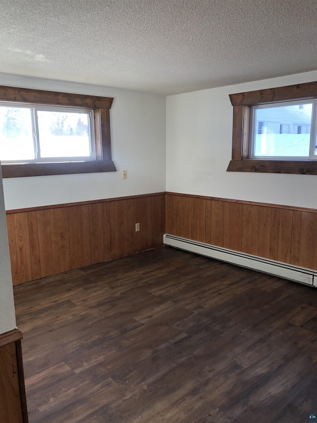 6509 Broadway St, Finlayson, MN 55735 - unfurnished room with a wainscoted wall, dark wood finished floors, a textured ceiling, and a baseboard heating unit