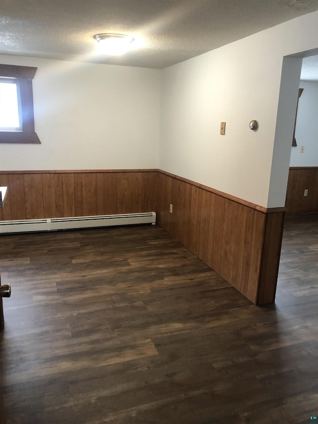 6509 Broadway St, Finlayson, MN 55735 - unfurnished room with a wainscoted wall, dark wood-type flooring, wood walls, a textured ceiling, and a baseboard heating unit