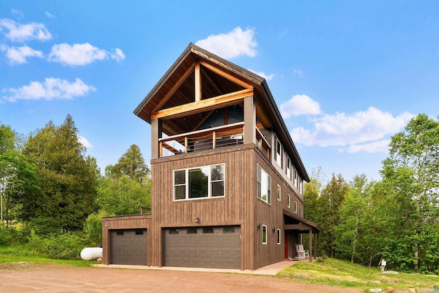 15 Big Cedar Trl, Lutsen, MN 55612 - view of side of home featuring a balcony, dirt driveway, and a detached garage