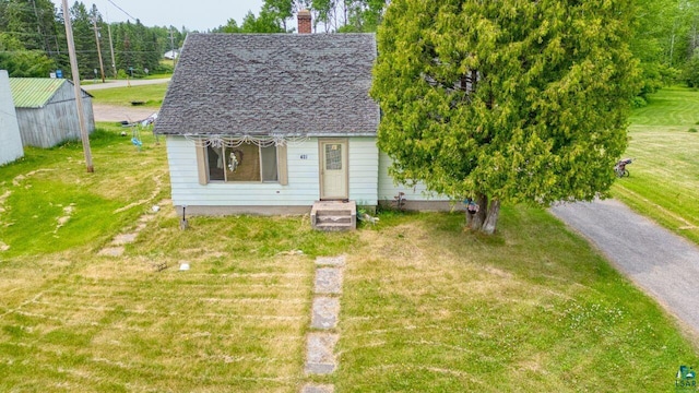 421 Main St S, Aurora, MN 55705 - view of front of house featuring a front lawn, a shingled roof, and a chimney