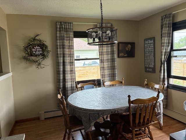 722 8th St S, Virginia, MN 55792 - dining area featuring baseboard heating, wood finished floors, a chandelier, plenty of natural light, and a textured ceiling