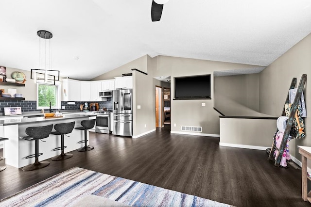 1464 Heather Ln, Cromwell, MN 55726 - kitchen featuring appliances with stainless steel finishes, dark wood finished floors, a kitchen bar, lofted ceiling, and white cabinetry