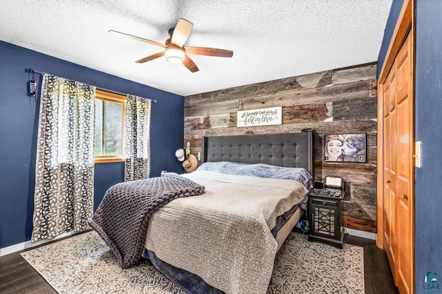 1464 Heather Ln, Cromwell, MN 55726 - bedroom featuring wooden walls, wood finished floors, an accent wall, ceiling fan, and a textured ceiling