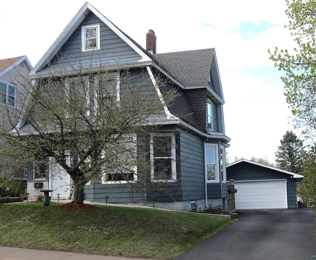 627 4th St, Proctor, MN 55810 - view of front of home with an outdoor structure, a chimney, a shingled roof, a detached garage, and a front yard
