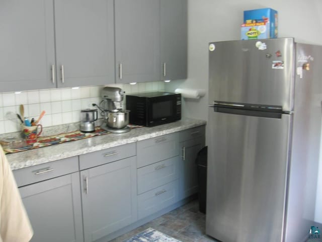 421 E Chapman St, Ely, MN 55731 - kitchen with freestanding refrigerator, black microwave, backsplash, and gray cabinetry