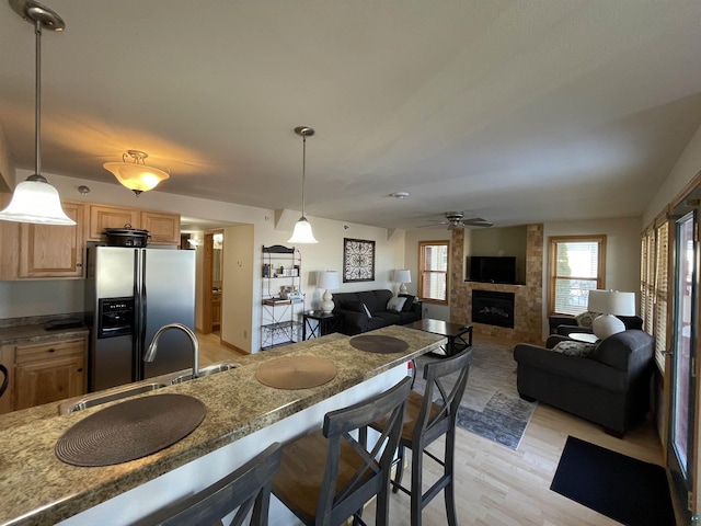 34 N 2nd St Unit 2, Bayfield, WI 54814 - kitchen with stainless steel refrigerator with ice dispenser, light wood-type flooring, a fireplace, light brown cabinets, and ceiling fan