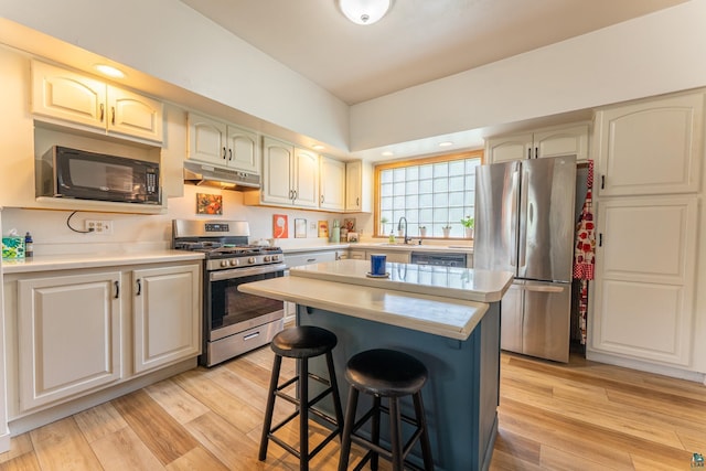 343 E Harvey St, Ely, MN 55731 - kitchen featuring stainless steel appliances, under cabinet range hood, a breakfast bar area, light countertops, and light wood finished floors