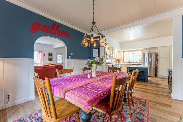 343 E Harvey St, Ely, MN 55731 - dining space with a chandelier, arched walkways, wainscoting, ornamental molding, and light wood-style floors