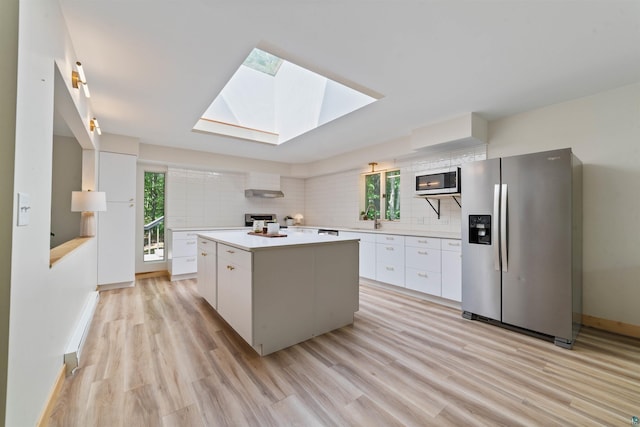 4921 W Pioneer Rd, Duluth, MN 55803 - kitchen featuring stainless steel appliances, white cabinetry, light wood-style flooring, a kitchen island, and backsplash