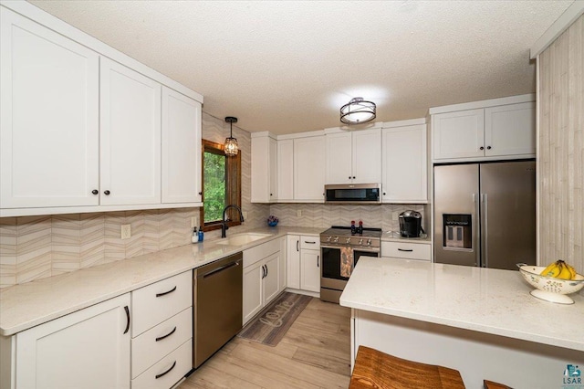 1819 Yosemite Ave, Duluth, MN 55811 - kitchen featuring stainless steel appliances, light wood finished floors, white cabinets, tasteful backsplash, and light stone countertops