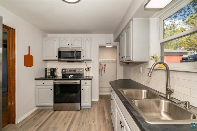 5521 Huntington St, Duluth, MN 55807 - kitchen featuring stainless steel appliances, dark countertops, backsplash, and light wood-type flooring