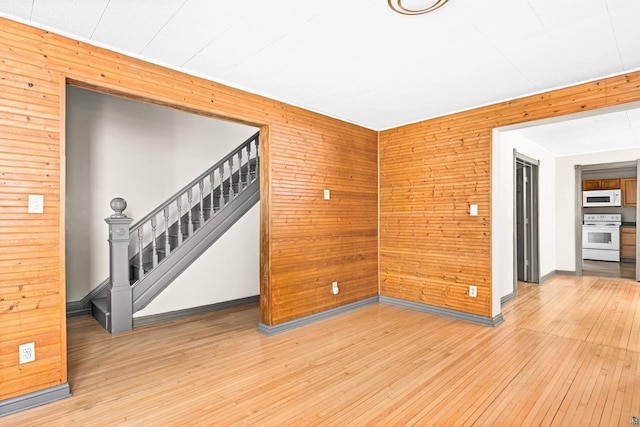 2626 W 5th St, Duluth, MN 55806 - empty room featuring wooden walls, stairway, and light wood-type flooring