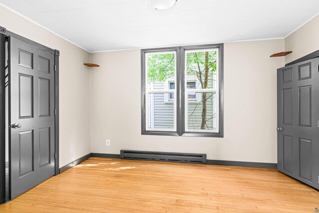 2626 W 5th St, Duluth, MN 55806 - unfurnished bedroom with a baseboard heating unit, light wood finished floors, and ornamental molding