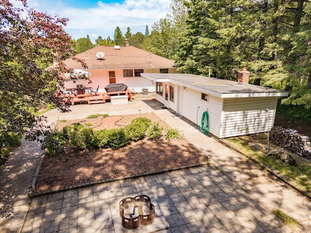 4750 Morris Thomas Rd, Hermantown, MN 55811 - rear view of house with a patio area, a wooden deck, an outdoor fire pit, and a chimney