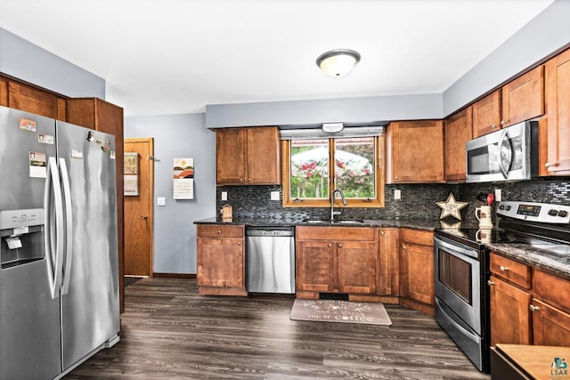 4750 Morris Thomas Rd, Hermantown, MN 55811 - kitchen with appliances with stainless steel finishes, dark wood-type flooring, brown cabinetry, decorative backsplash, and dark stone countertops