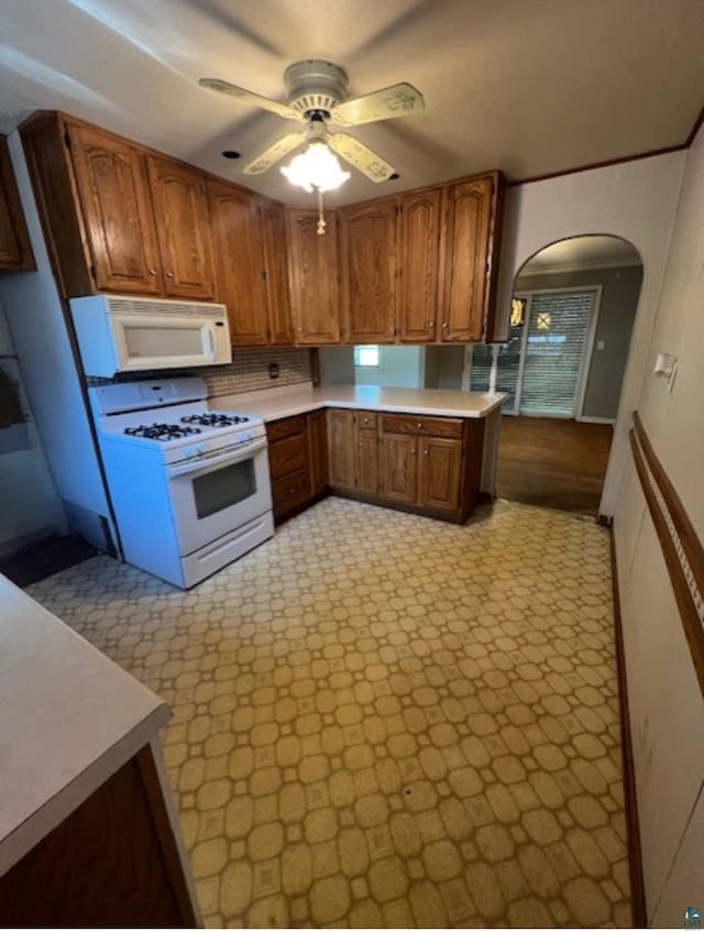 612 23rd St, Cloquet, MN 55720 - kitchen with white appliances, arched walkways, ceiling fan, brown cabinets, and light countertops