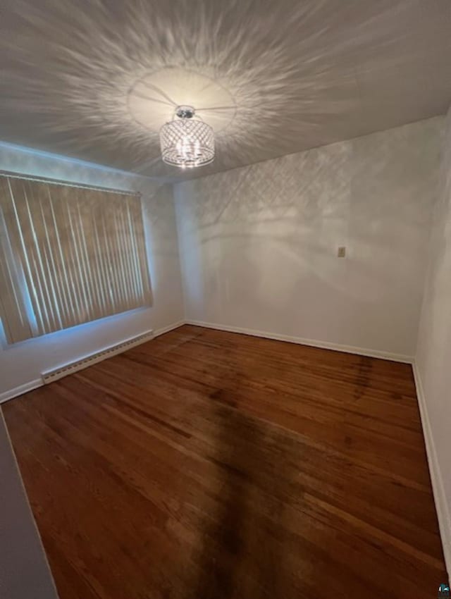 612 23rd St, Cloquet, MN 55720 - unfurnished room featuring wood finished floors, a chandelier, and a baseboard radiator