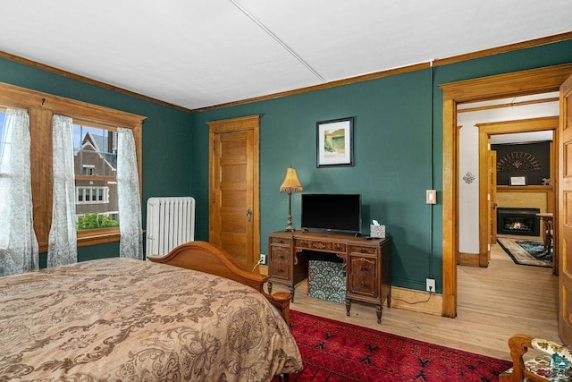 2319 E 4th St, Duluth, MN 55812 - bedroom featuring radiator heating unit, ornamental molding, wood finished floors, and a fireplace