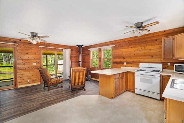 1612 Pequaywan Lake Rd, Ault, MN 55602 - kitchen featuring white gas range oven, ceiling fan, a peninsula, light countertops, and a wood stove