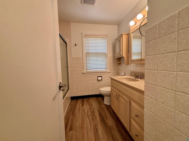 35 E Faribault St, Duluth, MN 55803 - bathroom featuring tile walls, vanity, wood finished floors, enclosed tub / shower combo, and wainscoting