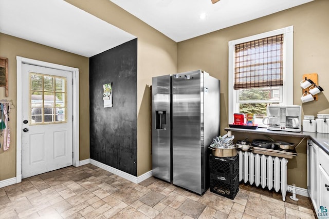 3801 W 5th St, Duluth, MN 55807 - kitchen with stainless steel fridge, radiator, stone tile flooring, and white cabinets