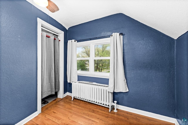 3801 W 5th St, Duluth, MN 55807 - bonus room featuring radiator, vaulted ceiling, a textured wall, wood finished floors, and ceiling fan