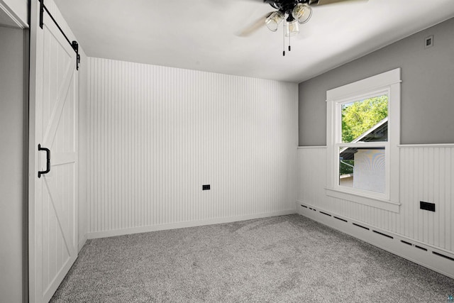 996 85th Ave W, Duluth, MN 55808 - carpeted empty room with a baseboard heating unit, a barn door, a ceiling fan, and a wainscoted wall