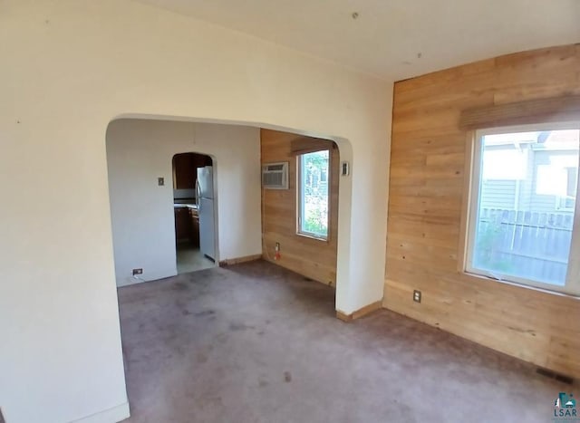 112 W 3rd Ave N, Aurora, MN 55705 - carpeted empty room featuring arched walkways, wooden walls, healthy amount of natural light, and an AC wall unit