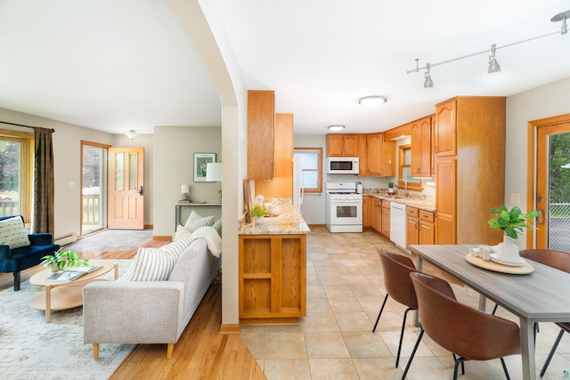 318 Marshall St, Duluth, MN 55803 - kitchen with white appliances, open floor plan, a baseboard heating unit, arched walkways, and light stone countertops