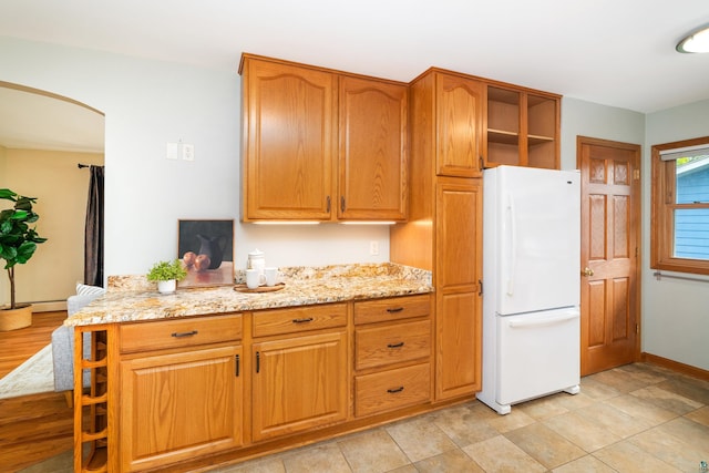 318 Marshall St, Duluth, MN 55803 - kitchen featuring freestanding refrigerator, arched walkways, light stone counters, open shelves, and brown cabinets