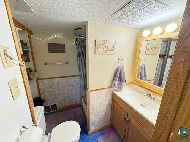 1339 92nd Ave W, Duluth, MN 55808 - full bathroom featuring tile walls, vanity, a wainscoted wall, a shower with shower curtain, and a textured ceiling
