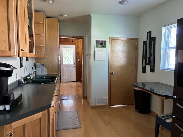 9235 Meadow St, Duluth, MN 55810 - kitchen with dark countertops, light wood-type flooring, glass insert cabinets, and brown cabinetry