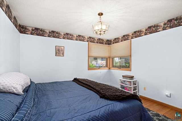 5525 Highland St, Duluth, MN 55807 - bedroom featuring wood finished floors, a chandelier, and a textured ceiling