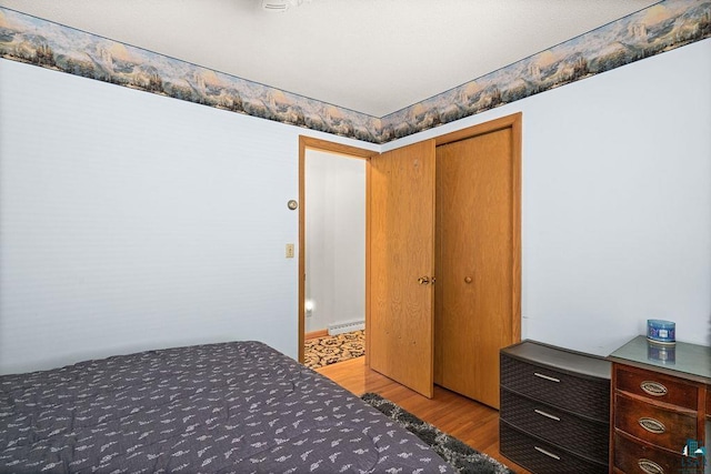 5525 Highland St, Duluth, MN 55807 - bedroom featuring wood finished floors, a closet, and a baseboard heating unit