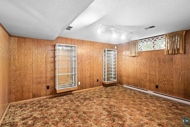 5525 Highland St, Duluth, MN 55807 - unfurnished room with a textured ceiling, rail lighting, wood walls, a baseboard radiator, and carpet flooring