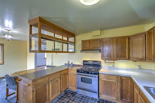 4128 Gladstone St, Duluth, MN 55804 - kitchen with gas range, under cabinet range hood, a peninsula, brown cabinetry, and dark tile patterned floors
