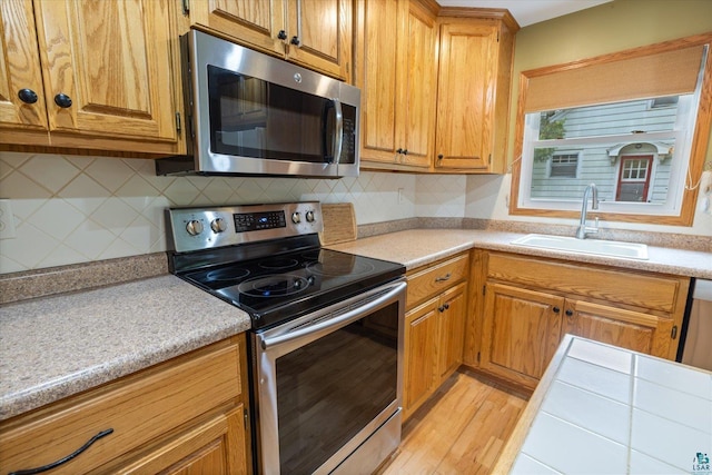 2323 Catskill St, Duluth, MN 55811 - kitchen with appliances with stainless steel finishes, light countertops, tasteful backsplash, and light wood-style floors