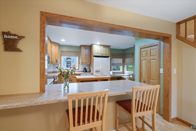 2323 Catskill St, Duluth, MN 55811 - kitchen featuring white refrigerator with ice dispenser, a peninsula, light countertops, a breakfast bar area, and light wood-type flooring