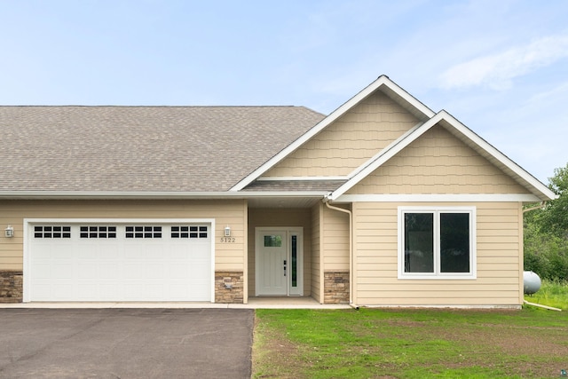 5122 Hermantown Rd Unit 5122, Hermantown, MN 55810 - craftsman-style house featuring driveway, a garage, roof with shingles, stone siding, and a front lawn