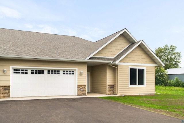 5122 Hermantown Rd Unit 5122, Hermantown, MN 55810 - view of front facade featuring stone siding, a garage, driveway, and roof with shingles