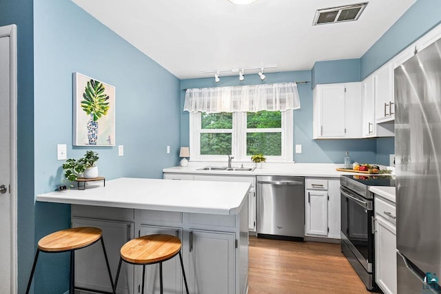 137 Madison Ave Unit 137, Duluth, MN 55811 - kitchen with stainless steel appliances, a breakfast bar, light countertops, dark wood-style flooring, and white cabinetry